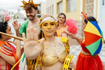 Selbstklebende Fototapeten Altes Krankenhaus Beelitz Woman raising her hand in a stop gesture to reject harassment during a Brazilian carnival street celebration, while friends support her around.  © kleberpicui