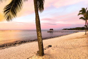 Scenic sunset over a tropical beach with a wooden pier and pavilion in Triolet, Mauritius
