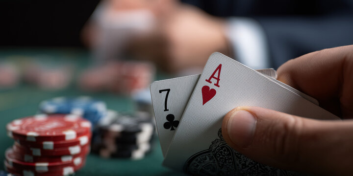 A poker player holding a winning hand of seven of clubs and ace of hearts