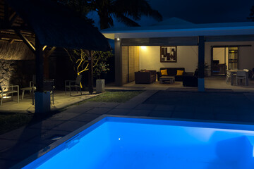 Modern luxury villa with illuminated private pool and garden at night in Tamarin, Mauritius