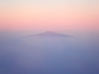 Fototapeta premium Profilo minimalista del vulcano Etna avvolto dalla nebbia al crepuscolo con cielo sfumato rosa e blu, Sicilia 1727