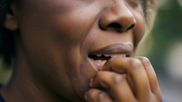 Close-up of a woman's face as she bites her nails and her nostrils flare