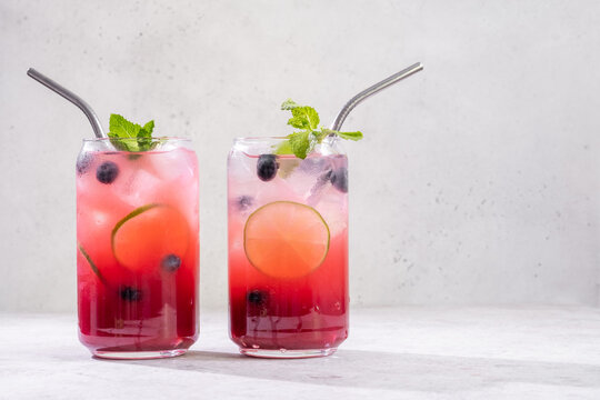 Fresh berry drinks with mint on a simple background