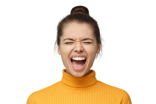Young woman in yellow turtleneck screaming with eyes closed, expressing anger