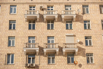 Obraz premium Residential building facade with windows, balconies, brick wall and sunlight shadows