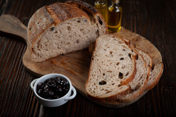 Rustic Olive Bread Presentation on Wood Background. Sliced Olive Bread on Dark Wooden Table. Artisan Olive Bread Slices on Rustic Background.