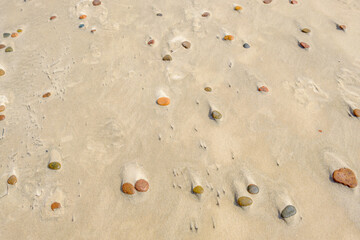 Colorful stones scattered on sandy beach surface Slowinski National Park Poland