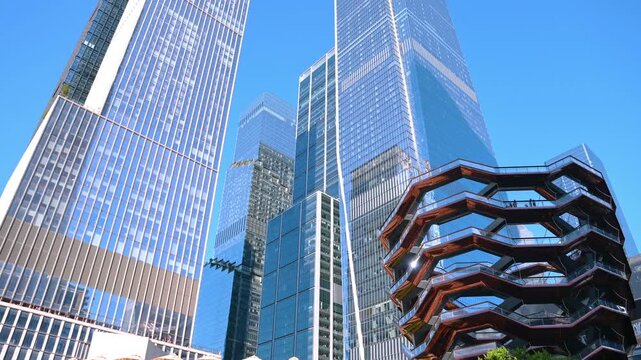 New York, USA, 8 July 2025: Stunning glass skyscrapers of Manhattan from low angle view. Famous tourist attraction - Vessel Sculpture in New York, USA.
