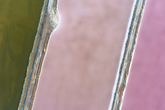 Aerial view of vividly colored evaporation ponds in shades of pink and green, contrasting sharply against the earthy tones of the surrounding landscape, Eilat, South District, Israel.