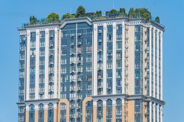 Obraz premium Multi-story residential building with classical architectural style, symmetrical facade, vertical windows, balconies, neutral color scheme, daytime lighting, elevated perspective, city backdrop