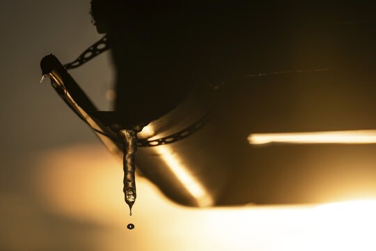 A drop of water comes off an icicle on a gutter in warm sunlight, back light, winter, Korpostr&ouml;m, Korpo or Korppo, Southwestern Archipelago, Finland