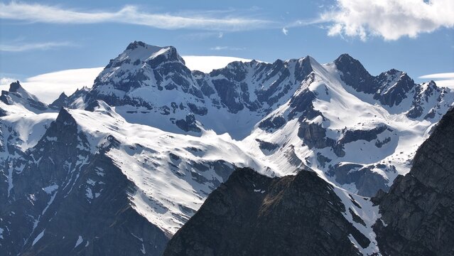 Aerial view of snow-capped mountains piercing the sky, a symphony of white against the stark, rocky terrain, Alpe Devero, Piemonte, Italy.