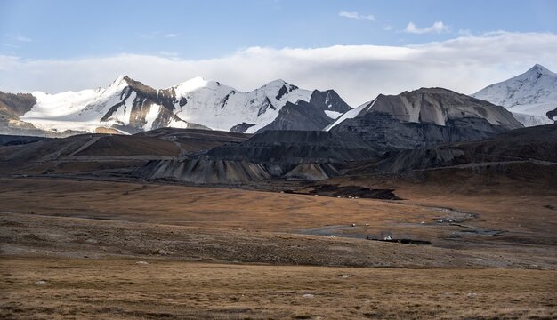 Autumnal plateau with brown grass, glaciated and snow-covered peaks, Ak Shyrak Mountains, near the Kumtor Gold Mine, Tian Shan, Kyrgyzstan
