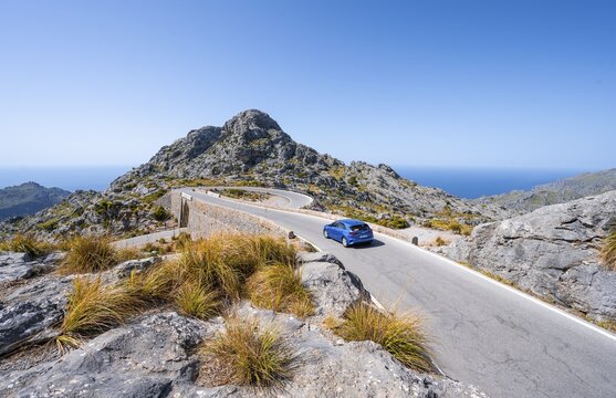 Car at the mountain pass with switchbacks to Sa Colobra, Nus de Sa Corbata road loop, Serra de Tramuntana, Majorca, Balearic Islands, Spain