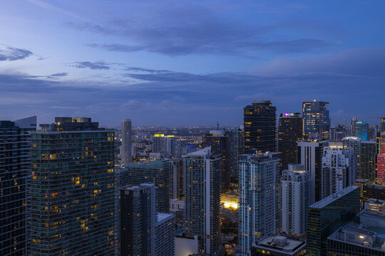 Aerial view of twinkling city lights ignite the towering skyscrapers under a dusky sky, Brickell, Miami, Florida, United States.
