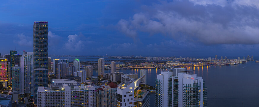 Aerial view of the city skyline with the towering buildings reflecting the last light of dusk over the waters of Biscayne Bay, Brickell, Miami, Florida, United States.