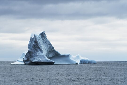 Iceberg drifting on the open sea against a dark cloudy sky, Disko Island, Qeqertarsuaq, West Greenland, Greenland