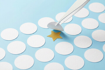 Tweezers revealing a gold star hidden under white paper circles as a concept of talent search or uniqueness