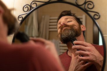 Man Trimming Beard in Bathroom Mirror at Home