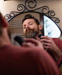 Man Trimming Beard in Bathroom Mirror at Home