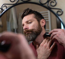 Man Trimming Beard in Bathroom Mirror at Home
