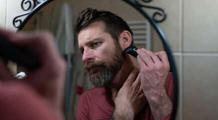 Man Trimming Beard in Bathroom Mirror at Home