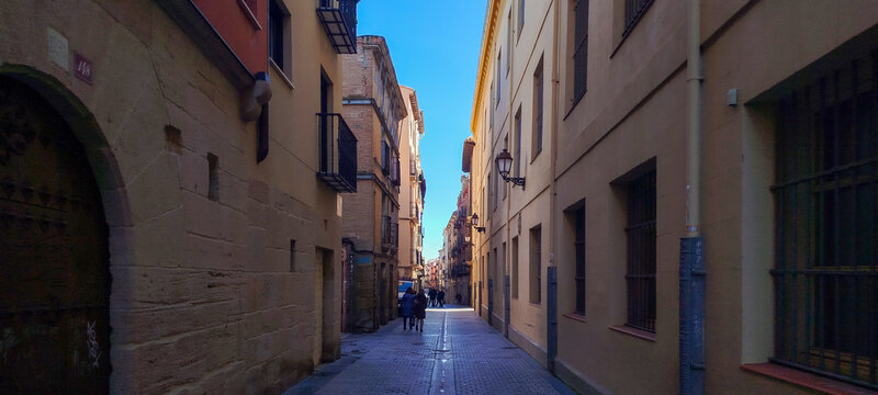 Calle peatonal estrecha y sombreada entre edificios de arquitectura tradicional bajo un cielo azul despejado en Logro&ntilde;o, Espa&ntilde;a