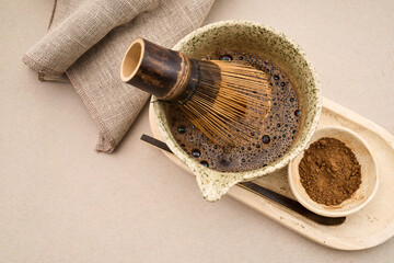 Preparing matcha tea with bamboo whisk and powder