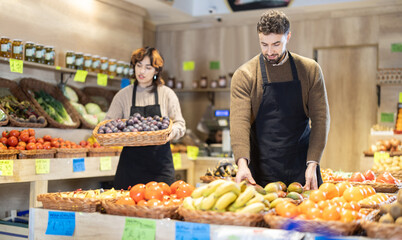 Eco food vegetable market, girl worker and mango. Man shop assistant add goods items in sales area....