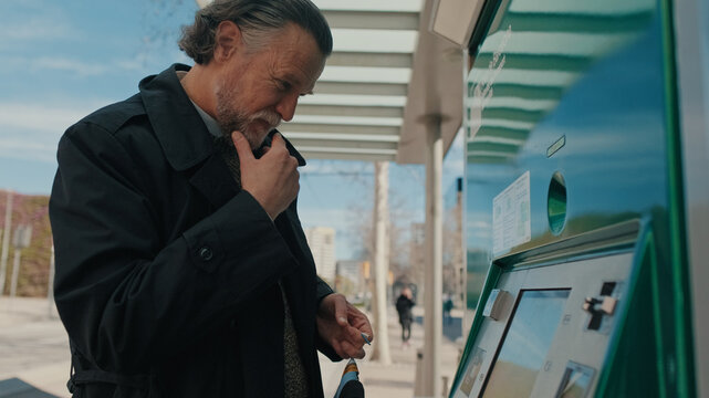 Older Man At Outdoor ATM Thinking