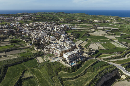 Aerial view of the Ta' Pinu Basilica amidst a patchwork of green fields meeting the azure sea, a serene landscape of Maltese beauty, Gharb, Ta Pinu bazilika, Malta.