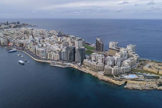 Aerial view of the coastal city with modern buildings and historical fortifications meeting the deep blue sea, Sliema, Valletta, Malta.