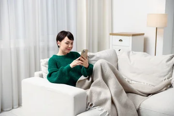 Fotobehang Onderzeeër Woman using smartphone on sofa at home. Space for text  © New Africa