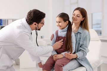 Obraz premium Little girl and her mother having appointment with pediatrician in hospital. Doctor checking child with stethoscope