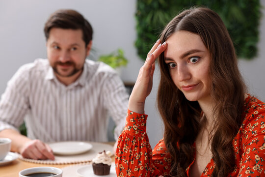 Bad date. Embarrassed woman ignoring flirting man at table during dinner indoors, selective focus