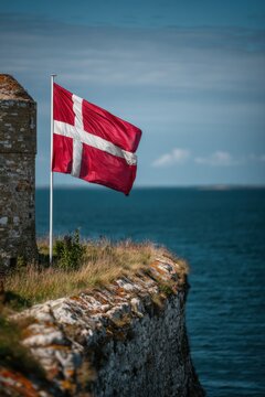 Flag waves on a cliff near Kronborg Castle in Denmark on a clear day Generative AI
