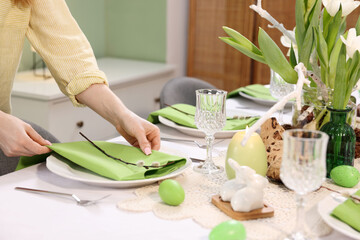 Woman setting festive table for Easter celebration at home, closeup