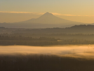 At dawn, the scenic Mount Hood rises from the forested landscape of northern Oregon. This iconic Pacific Northwest mountain is part of the Cascade Mountain Range.