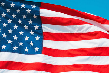 Obraz premium Waving American flag against a clear blue sky, symbolizing patriotism and national pride in the USA.