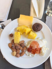 Breakfast in a restaurant with fresh sliced ​​fruits and vegetables with pancakes and diet food on a white plate on the table