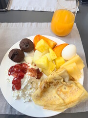 Breakfast in a restaurant with fresh sliced ​​fruits and vegetables with pancakes and diet food on a white plate on the table