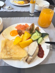 Breakfast in a restaurant with fresh sliced ​​fruits and vegetables with pancakes and diet food on a white plate on the table