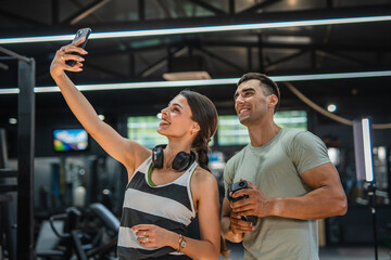 Fototapeta premium sports man and woman couple, friends take a self portrait at gym