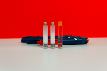 Insulin pen, insulin medical cartridges for use in insulin syringe pens for diabetic patients. Red background.