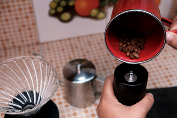 Close up of woman using pouring beans coffee on manual grinder while preparing fresh coffee in a kitchen,brewing coffee V60. 