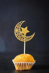 One freshly baked cupcake with crescent moon and star decoration.