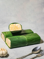 Tempeh wrapped in banana leaves with a marble background. Tempeh is a traditional Indonesian food made from soybeans. It is beneficial for health.