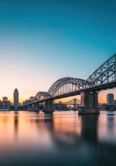 Naklejka premium A scenic view of multiple massive steel bridges crossing a wide river under an expansive sky, showcasing urban architecture and reflections on the flowing water, bridge, tourism, curve