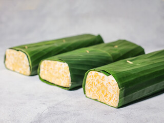 Tempeh wrapped in banana leaves with a marble background. Tempeh is a traditional Indonesian food made from soybeans. It is beneficial for health.