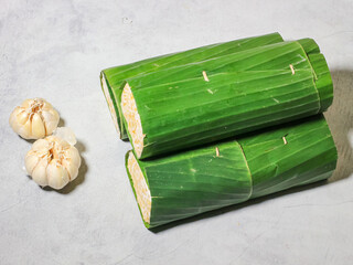 Tempeh wrapped in banana leaves with a marble background. Tempeh is a traditional Indonesian food made from soybeans. It is beneficial for health.